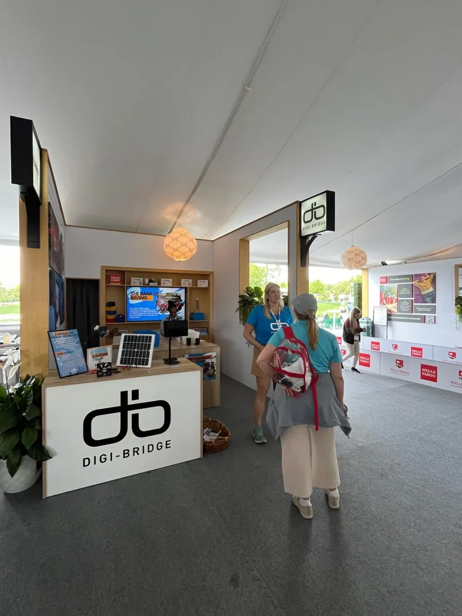 The completed activation in use, with the same counter, hanging blade sign, screens, and printed wall, and visitors walking through.