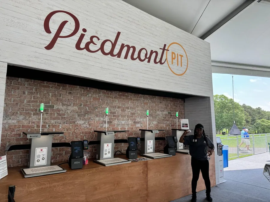 A concession build with a painted brick-look fascia, script identification, and a long timber counter fitted with point-of-sale stations.