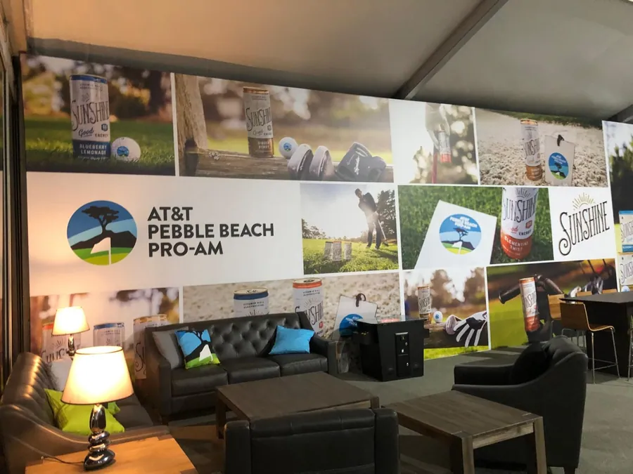 A hospitality lounge wall covered by a large-format printed photographic collage above leather seating and lamps.